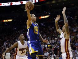 Stephen Curry (c) de los Golden State Warriors entre Norris Cole (i) y Michael Beasley (d) de Miami Heat durante el partido. AP /