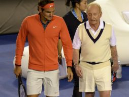 Laver, de 75 años, entró a la cancha que lleva su nombre en pantalones cortos y un chaleco, para jugar contra Federer. AP /
