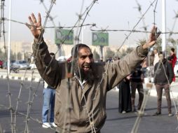 Un manifestante muestra el saludo de los 'cuatro dedos' tras un alambre de espino instalado en la entrada de la Academia de Policía. EFE /