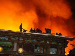 Los bomberos trabajan para apagar el incendio en el antiguo pueblo tibetano de Yunnan. AFP /