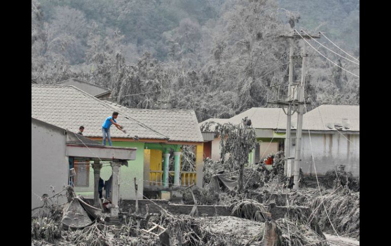 Habitantes de Sumatra limpian los techos de sus casas de las cenizas expulsadas por el volcán. AP /