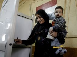 Aquí una mujer con su hijo emitiendo su sufragio este martes. AP /