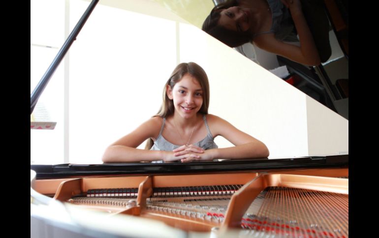 La joven posa para la cámara junto a su piano. ARCHIVO /