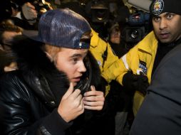 El cantante salió de una camioneta negra vestido con un abrigo y una gorra. AP /