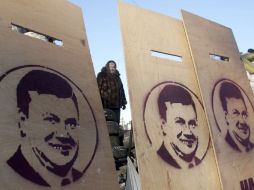 Una manifestante permanece detrás de unos tablones de madera con el retrato del presidente de Ucrania, Víktor Yanukóvich. EFE /