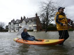 Un hombre remolca a una mujer a bordo de una piragua en una calle inundada en Datchet, cerca de Londres. EFE /
