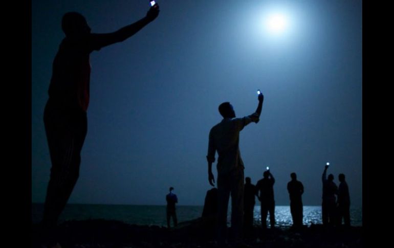 ''Señal'' muestra a inmigrantes africanos en Yibuti levantando sus teléfonos para capturar una red telefónica de bajo coste de Somalia. AP /