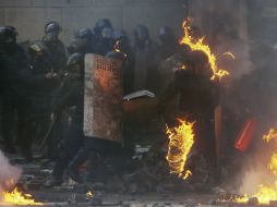 Un policía antidisturbios, envuelto en llamas durante los choques entre opositores y policía después de varias semanas de tregua. EFE /