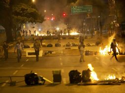 Opositores bloquean una calle de Caracas con fragmentos de mobiliario urbano y bolsas de basura incendiadas. AP /