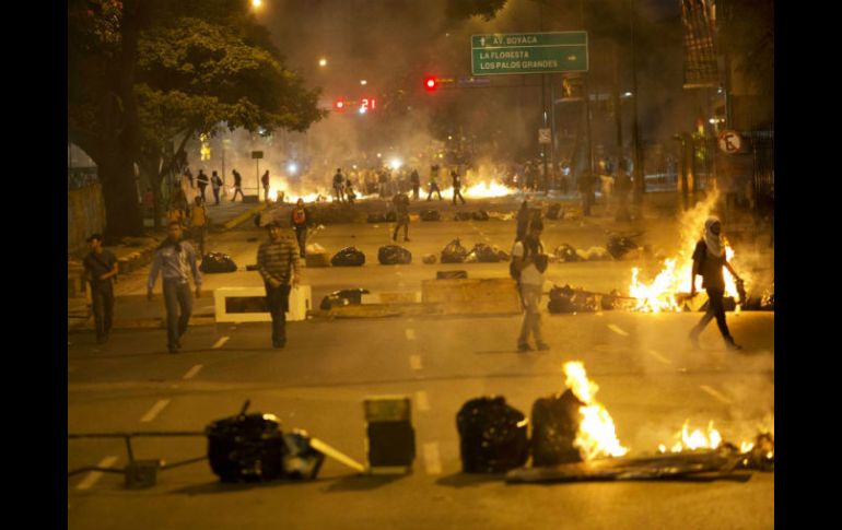 Opositores bloquean una calle de Caracas con fragmentos de mobiliario urbano y bolsas de basura incendiadas. AP /