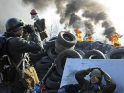 Un manifestante antigubernamental utiliza unos prismáticos durante otra jornada de protestas en una barricada en Kiev. EFE /