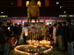 La gente recuerda a las víctimas con veladoras en el lugar del crimen. AP /