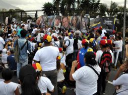 Manifestantes pegan pancartas con rostros de las personas caídas durante las protestas en contra de Maduro. NTX /