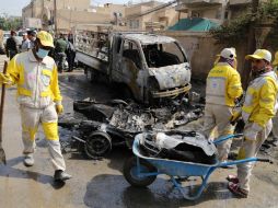 Trabajadores municipales de Bagdad trabajan para limpiar la zona donde explotó un coche bomba. AP /
