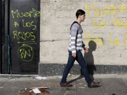 Un hombre camina a primera hora por Chacao, Caracas, frente a un grafiti que fue escrito durante las protestas. EFE /