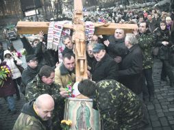 Católicos ucranianos cargan una enorme cruz de madera en una procesión religiosa en Kiev. AFP /