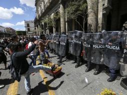 Jóvenes manifestantes lanzan objetos contra los escudos de la policía antimotines.  /