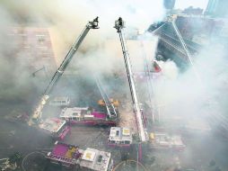 Bomberos sofocan incendios en la zona de Harlem donde ocurrió la explosión de gas que colapsó dos edificios de departamentos. AP /