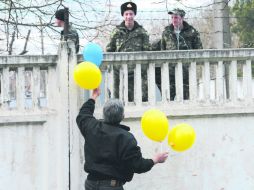 Un hombre comparte globos con los colores de la bandera nacional de Ucrania mientras habla con soldados ucranianos, en Bakhchisarai. AFP /