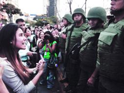 Ponen orden. Una manifestante encara a varios agentes de la Guardia Nacional, en la Plaza Altamira, en Caracas, al ser desalojados. AP /