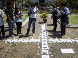 Personas observan una cruz formada con imágenes de las personas fallecidas a causa de las protestas. EFE /