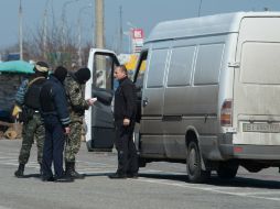 Soldados rusos verifican documentos y automóviles en un punto de revisión en un camino que viene de Ucrania hacia Crimea. AFP /