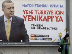 Una turca revisa su móvil delante de un cartel con la imagen del primer ministro turco, Erdogan, incriminado en actos de corrupción. EFE /
