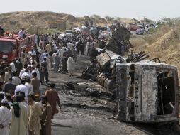 Rescatistas, polícias y civiles rodean los restos del accidente, donde dos camionetas de pasajeros chocó contra un camión de gasolina. AP /
