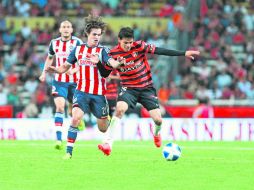 Sangre nueva. Los juveniles Carlos Fierro, de Chivas, y el rojinegro ''Pochito'' González disputan el esférico durante el duelo.  /