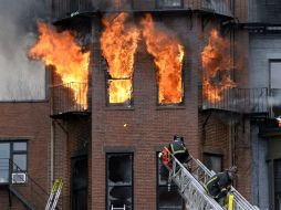 Bomberos lanzan cuatro escaleras contra el edificio para luego dirigir chorros de agua para contener el fuego. AP /
