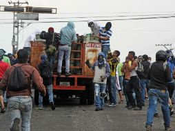 Manifestantes saquean un camión lleno de cilindros de gas durante una protesta contra Nicolás Maduro. AFP /
