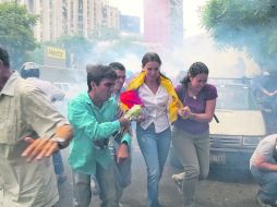 La ex diputada Corina Machado (al centro) es ayudada por sus simpatizantes para salir de la manifestación reprimida por la Policía. EFE /