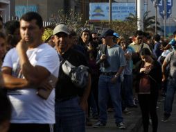 Personas esperan a las afueras de un centro comercial en Iquique. AP /