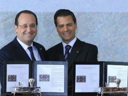 El presidente de Francia, François Hollande (i), y su homólogo de México, Enrique Peña Nieto (d), muestran la cancelación de un timbre. EFE /