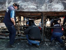 Peritos inspeccionan los restos del autobús de pasajeros. AP /