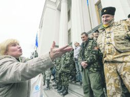 Exigen dimisión.  Una mujer grita ante un grupo de militares que custodian la entrada al edificio que alberga el Parlamento, en Kiev. EFE /