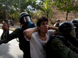 Elementos de la Guardia Nacional Bolivariana detienen a uno de los jóvenes durante el enfrentamiento. AP /