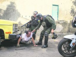 Miembros de la Guardia Nacional Bolivariana tratan de someter a un manifestante que se ocultaba bajo un camión. EFE /