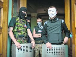Militantes prorrusos en uniformes custodian la puerta de la estación de televisión regional de Donetsk. EFE /
