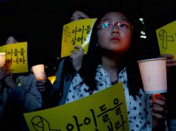Ciudadanos rinden encienden veladoras por los cuerpos de las personas atrapadas en el ferry. EFE /