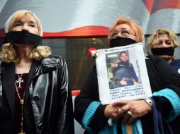 Familiares de víctimas se protestaron ante el convoy tapándose la boca con una cinta negra, pues no están deaucerdo con la desición. AFP /