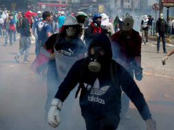 Manifestantes caminan entre el gas lacrimógeno lanzado por la policía. AP /