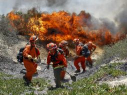 Bomberos en Riverside se retiran a un terreno más alto cuando las llamas comienzan a desplazarse hacia ellos. AP /