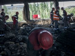 Decenas de trabajadores, con sobretodos y cascos, retiran las barricadas en el exterior del edificio de gobierno. AP /