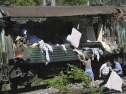 Varios miembros de un equipo de emergencias examinan los daños de un vagón tras un accidente entre dos trenes. EFE /