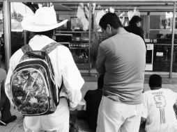 Frente a un aparador empañado, 18 hombres silenciosos ven el partido de México-Camerún.  /