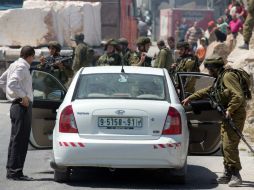 Soldados inspeccionan vehículos en busca de los jóvenes. AFP /