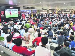 Atención. Espectadores de todas las nacionalidades observan un partido del Mundial en un aeropuerto brasileño. AFP /