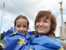 Una mujer y su hija celebran el acuerdo de asociación envueltas en banderas de la UE y Ucrania. AFP /