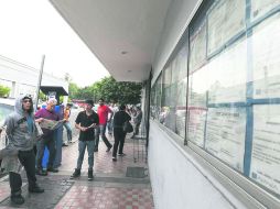 Desempleo. Personas desocupadas checan las vacantes afuera de una agencia de colocación en busca de una oportunidad laboral.  /